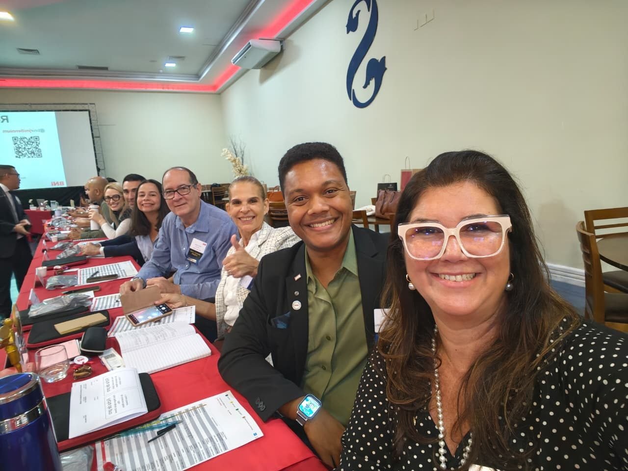 Participantes conversando à mesa, com a sala da reunião ao fundo.