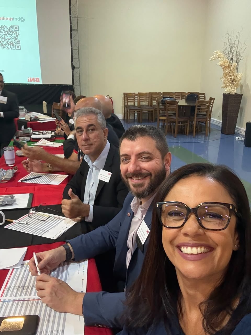 Participantes sentados à mesa, com fichas de reunião e anotações.